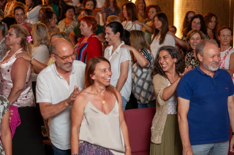 Participantes de pé a rir, de mãos nos ombros uns dos outros, no Seminário Educar Hoje